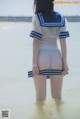 A woman in a sailor outfit standing in the water.