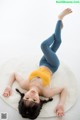 A woman laying on a white rug with her legs up.