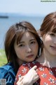 Two young women standing next to each other near the water.