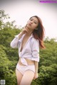 A woman in a white shirt and panties posing for a picture.