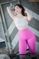 A woman in a white top and pink leggings posing for a picture.