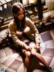 A woman sitting on a tiled floor next to a window.