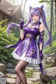 A woman in a purple and white dress standing in a forest.