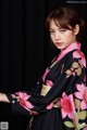 A woman in a black and pink kimono posing for a picture.